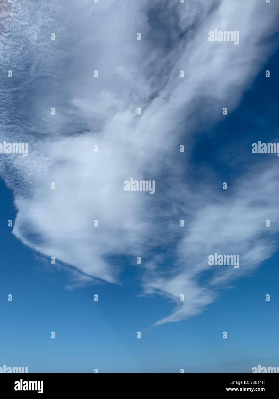 Ungewöhnliche Wolkenformation, die sich in einen Punkt, den blauen Himmel, wirbelt und hinunterwirbelt Stockfoto