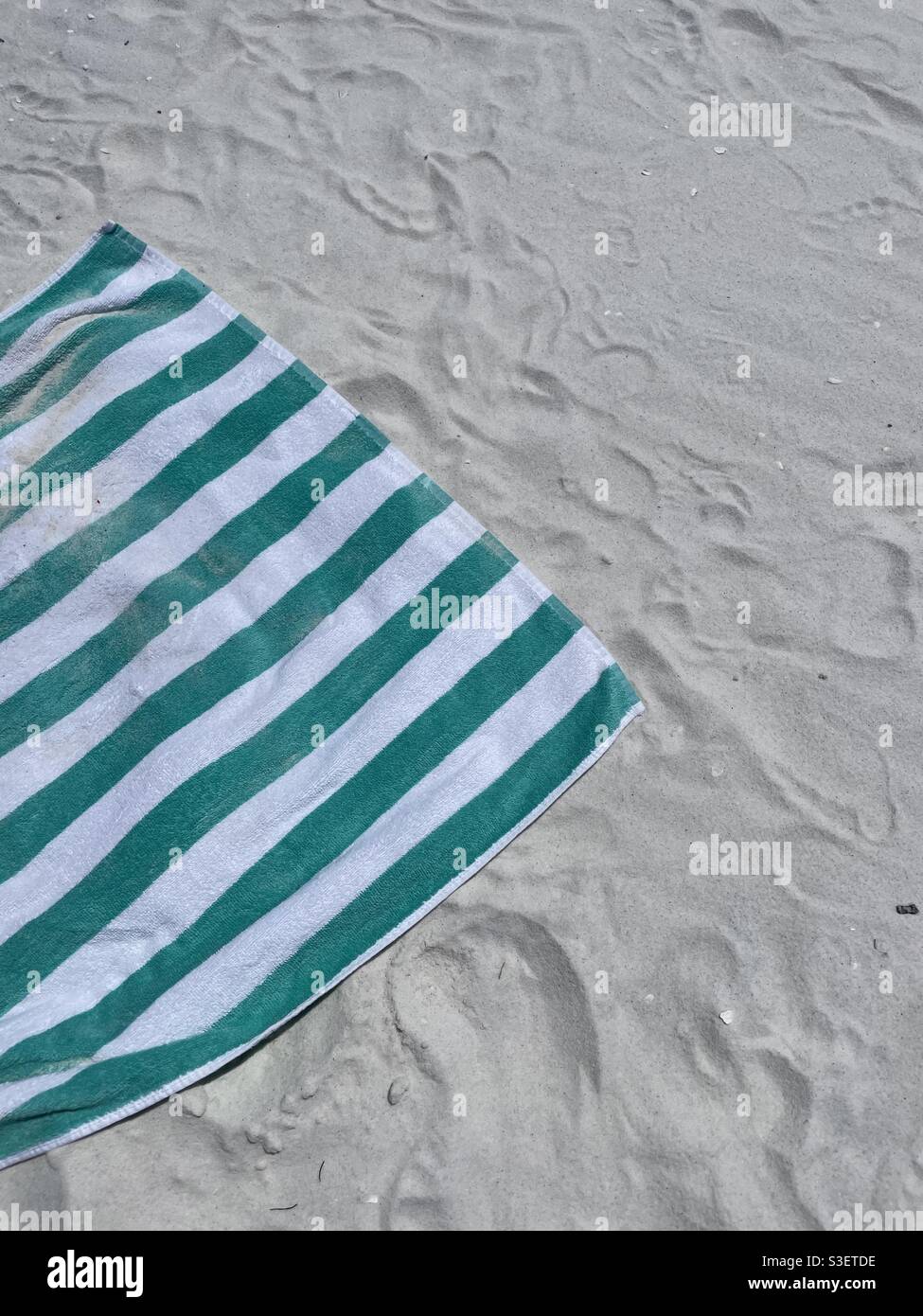 Grünes und weißes Strandtuch am weißen Sandstrand Stockfoto