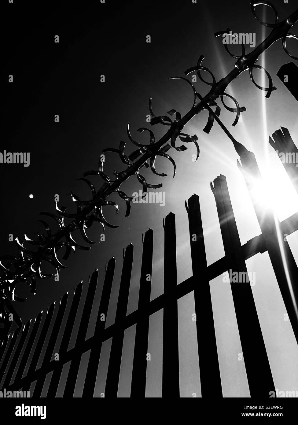 Metallzäune und Stacheldraht in einer dunklen Warnung vor Hausfriedensbruch und Hausfriedensbruch - Smartphone-aufgenommenes Stockfoto