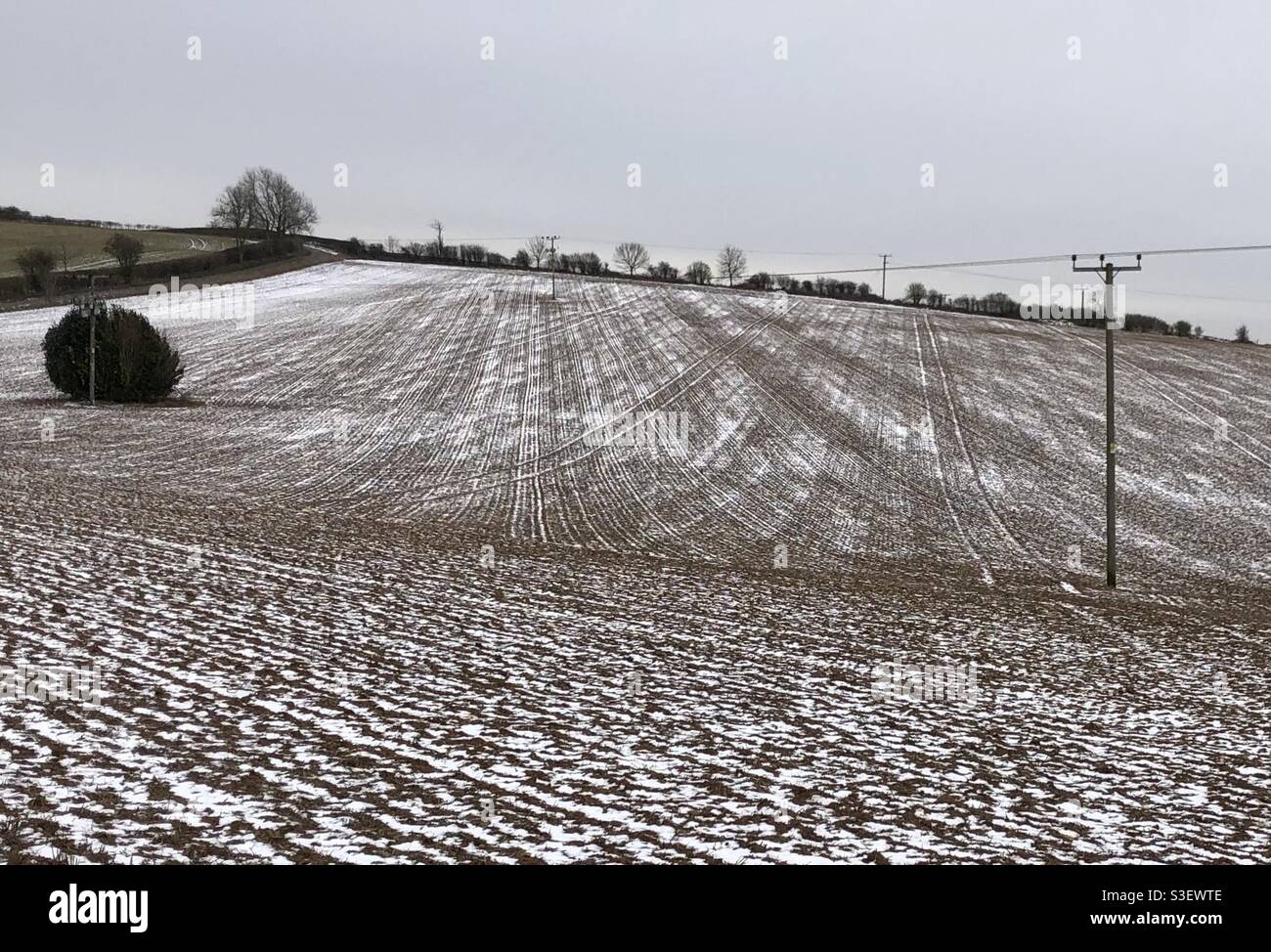 Winterlandschaft ein gepflügtes Feld seine Furchen mit Schnee geätzt In den hohen Cotswolds Stockfoto