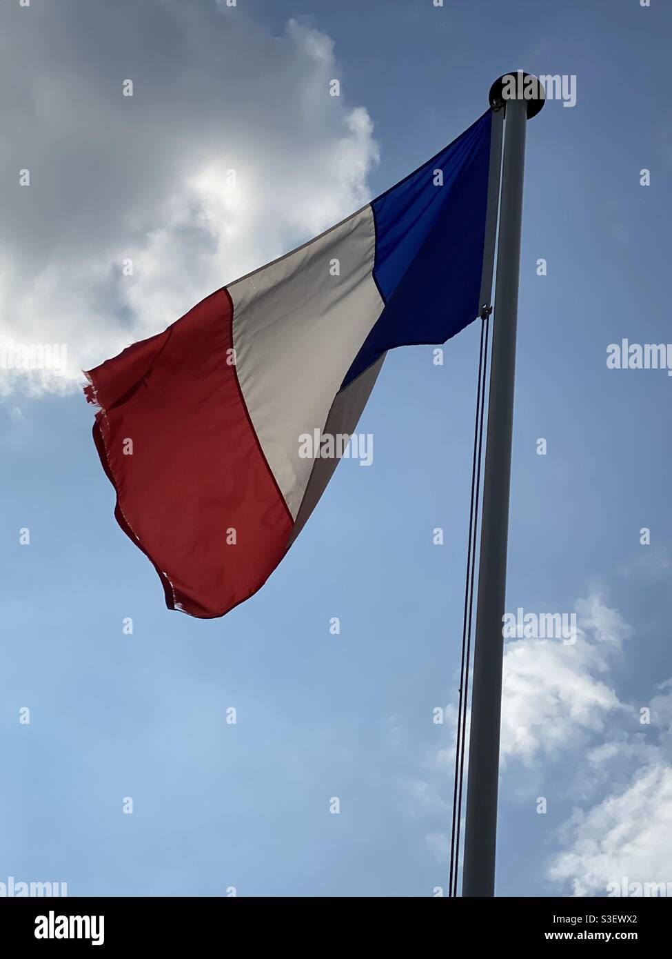 Französische Flagge auf einem Mast, der im Wind schwebt Ein blauer Himmel Stockfoto