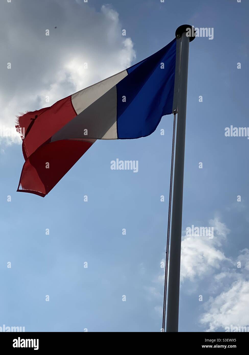 Französische Flagge auf einem Mast, der im Wind schwebt Blauer Himmel Stockfoto