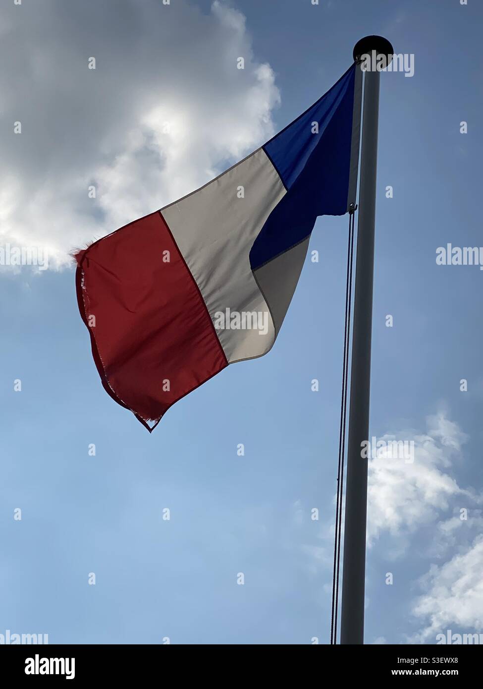 Französische Flagge auf einem Mast in der schwimmenden zerrissen Wind in blauem Himmel Stockfoto