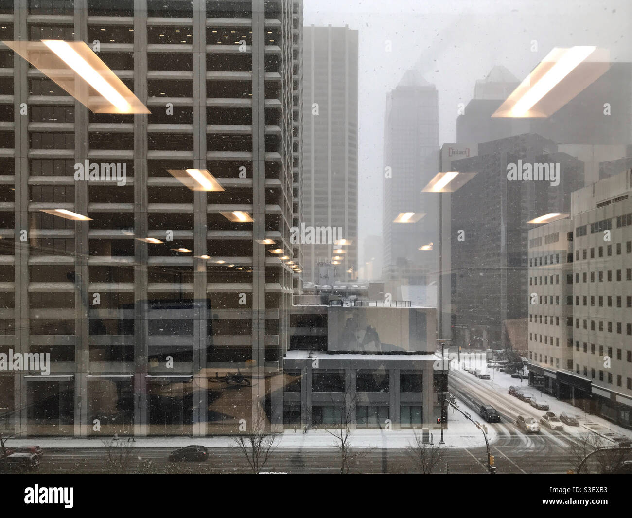 Blick aus dem Inneren eines warmen Bürogebäudes auf die kalte, verschneite Welt draußen. Calgary, Alberta, Kanada. Stockfoto