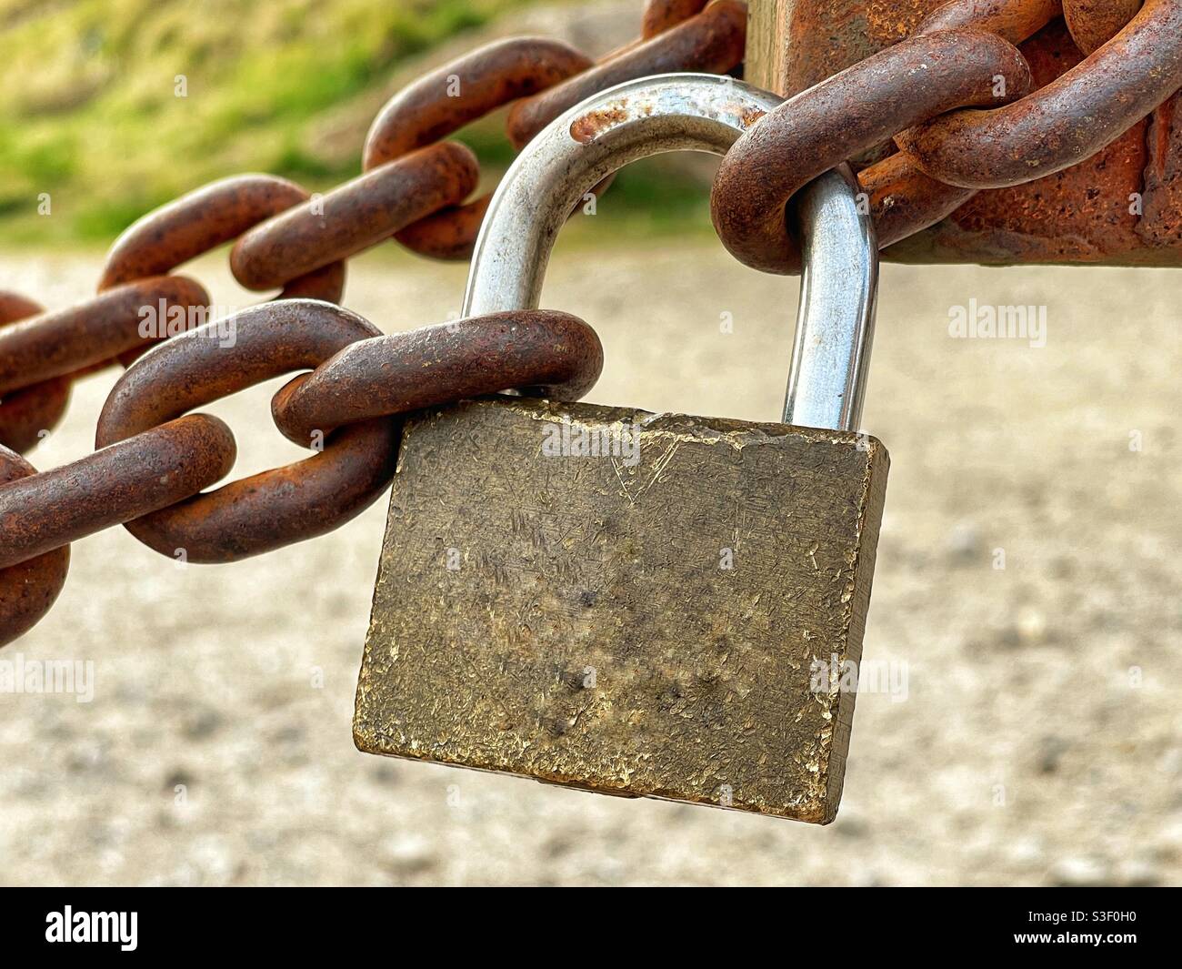 Nahaufnahme eines Vorhängeschlosses, das eine schwere Metallkette sichert Stockfoto