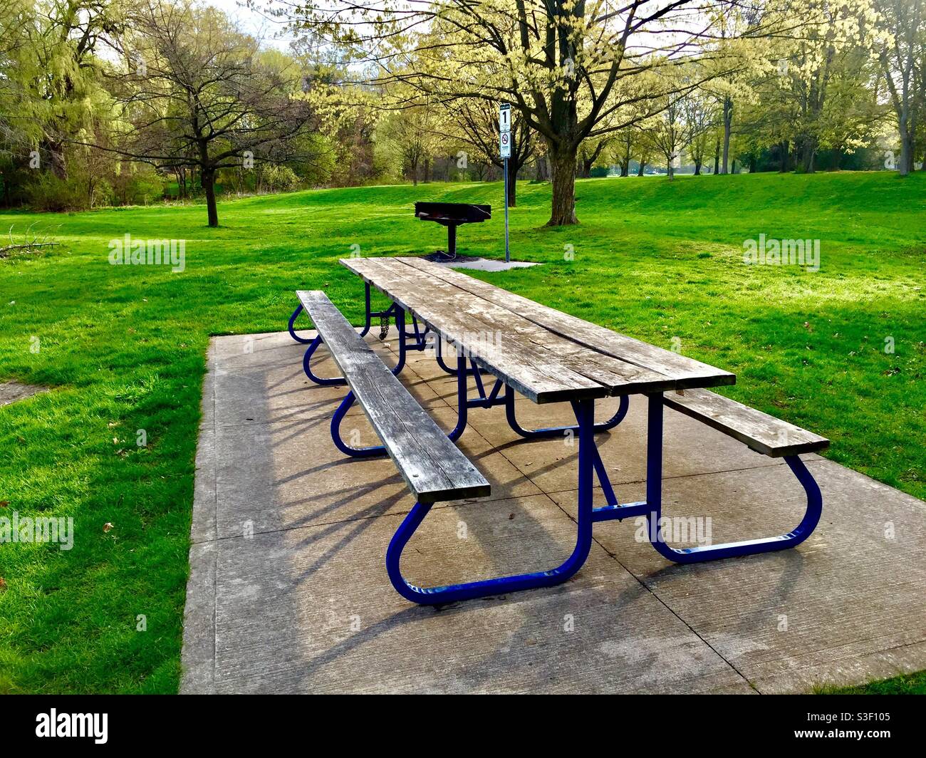 Ein leerer Picknickplatz in einem schönen Park mit einem Grill, einem Picknicktisch und einer langen, angeschlossenen Bank, Ontario, Kanada. Covid-Beschränkungen für Versammlungen halten Menschen fern, hoffentlich nicht lange. Stockfoto