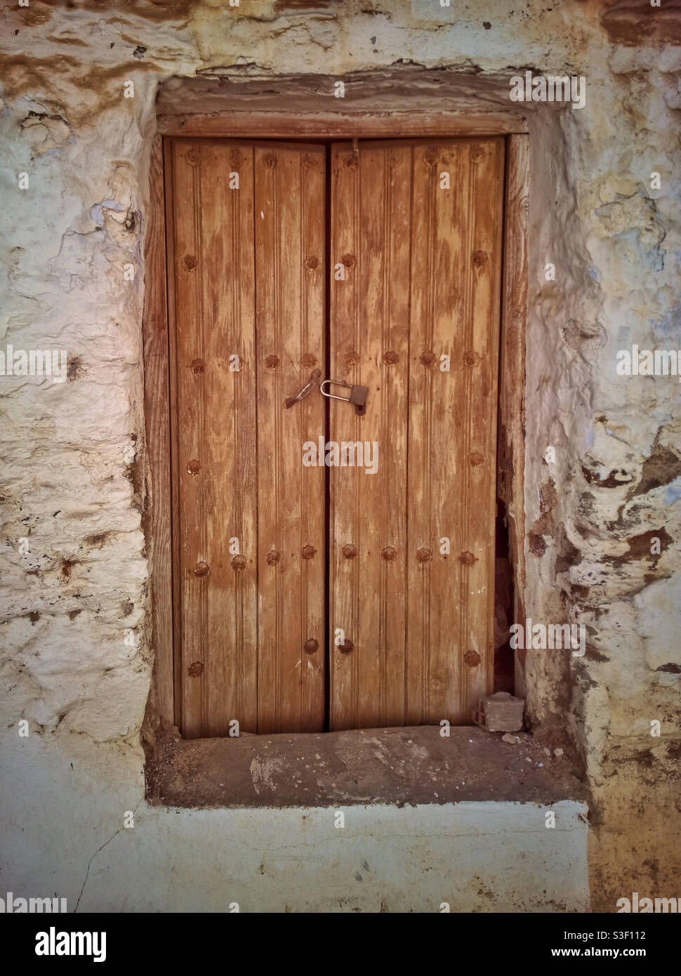Alte rustikale Tür in einem weiß ummauerten Grundstück in Andalusien, Spanien. Stockfoto