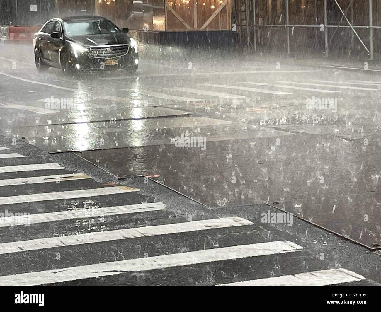 Ein Auto fährt während eines fahrenden Regensturms, 2021, USA, an eine Kreuzung in New York City Stockfoto