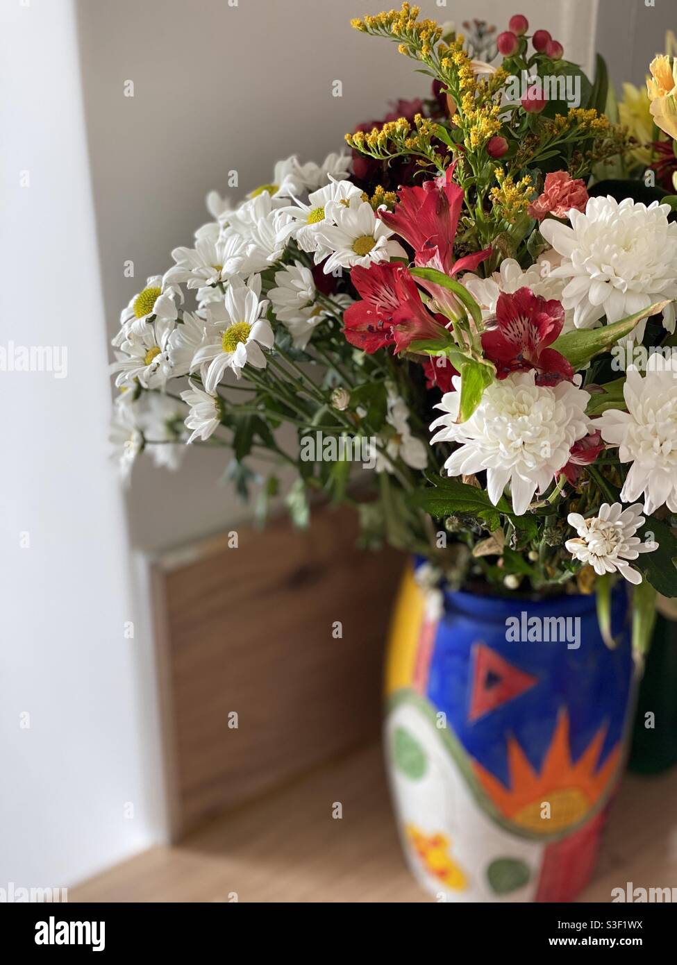 Mehrfarbiger Blumenstrauß in einer mehrfarbigen Vase mit verschwommenem Hintergrund Stockfoto