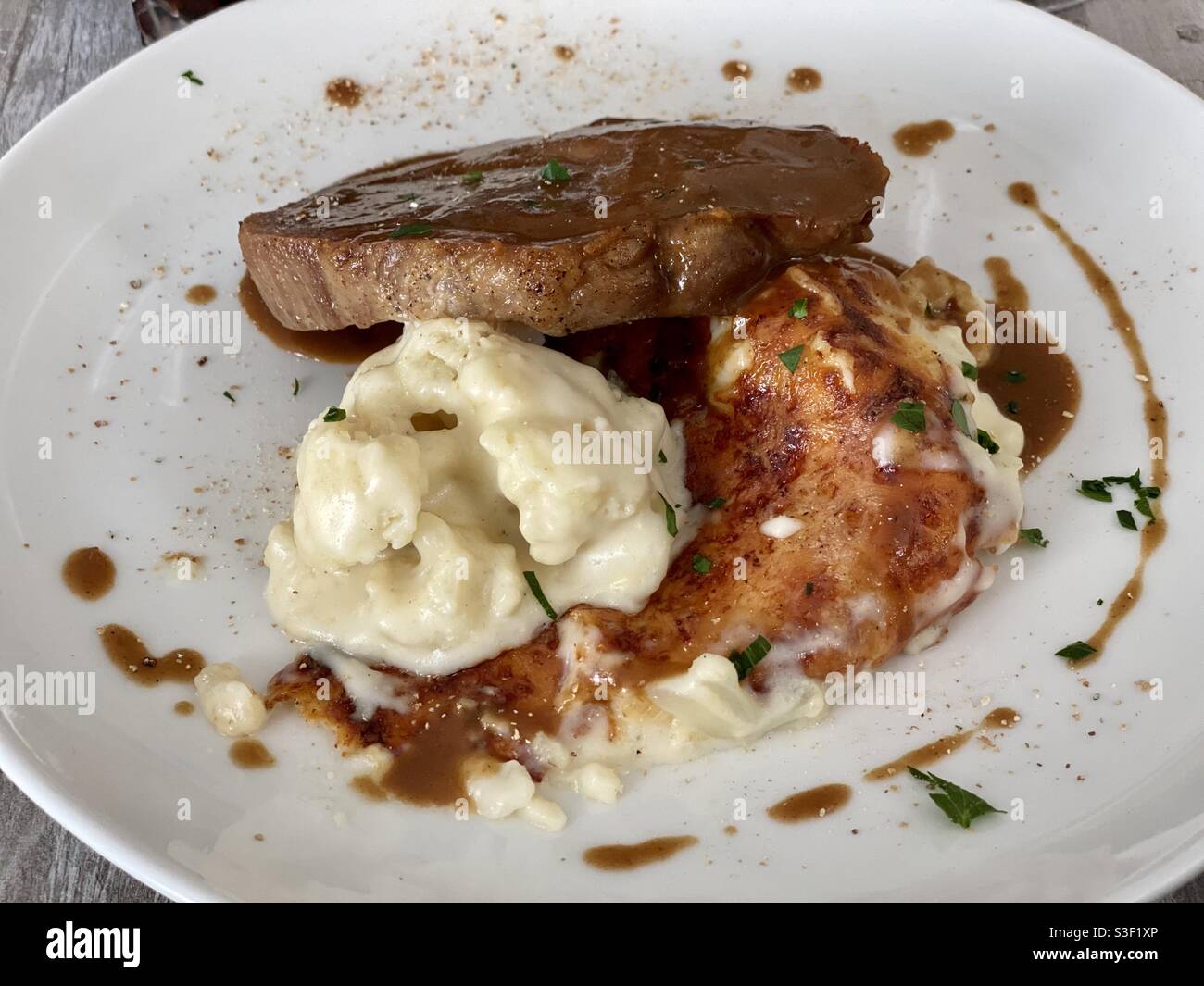Rindersteak oder porc hacken Teller mit Kartoffeln oder Blumenkohlpüree und Käsegratinierung mit Sauce - Smartphone-aufgenommenes Stockfoto