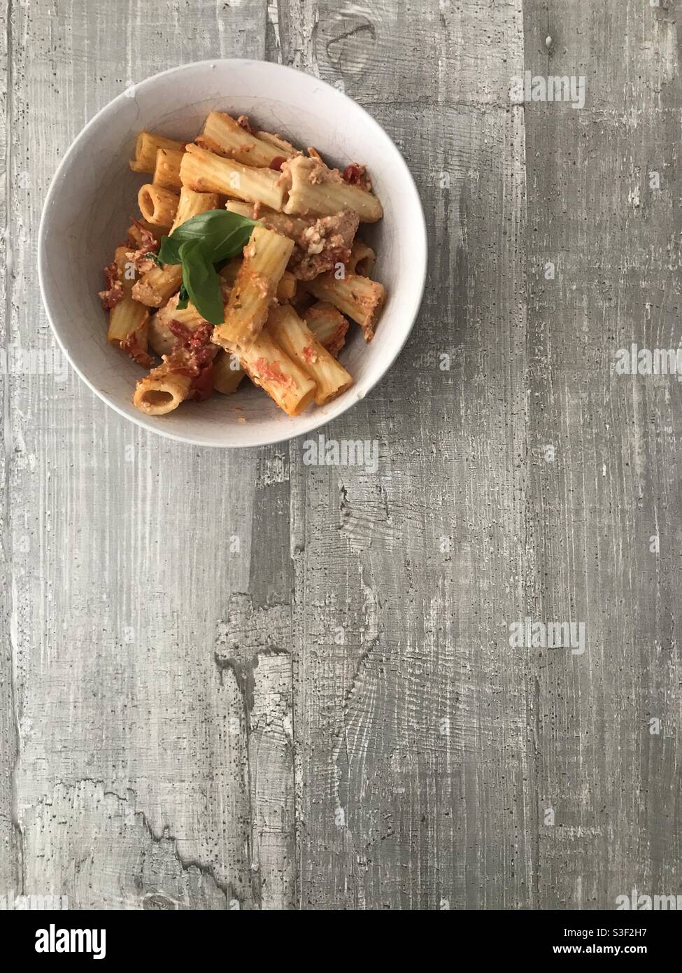 Eine Schüssel mit Rigatoni-Nudeln mit Tomaten, Feta und Basilikumsoße ...
