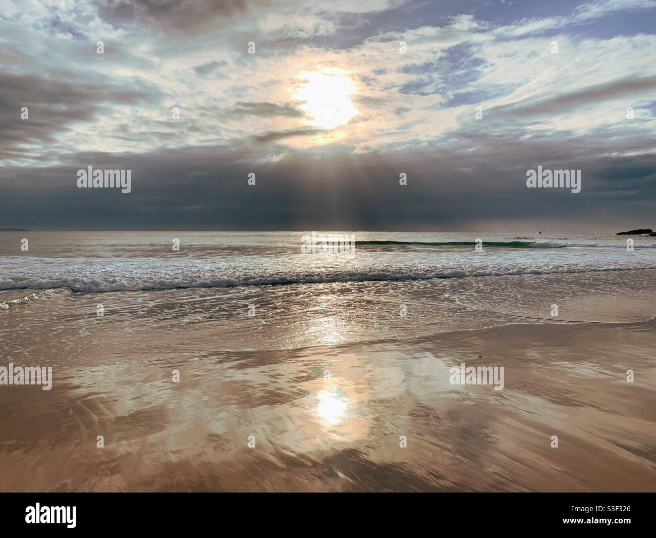 Sonnenaufgang über dem Pazifischen Ozean NSW Australien. Durch vereinzelte Wolken schimmern und sich im nassen Sand spiegeln, was am Strand eine Art Bokeh-patten macht Stockfoto