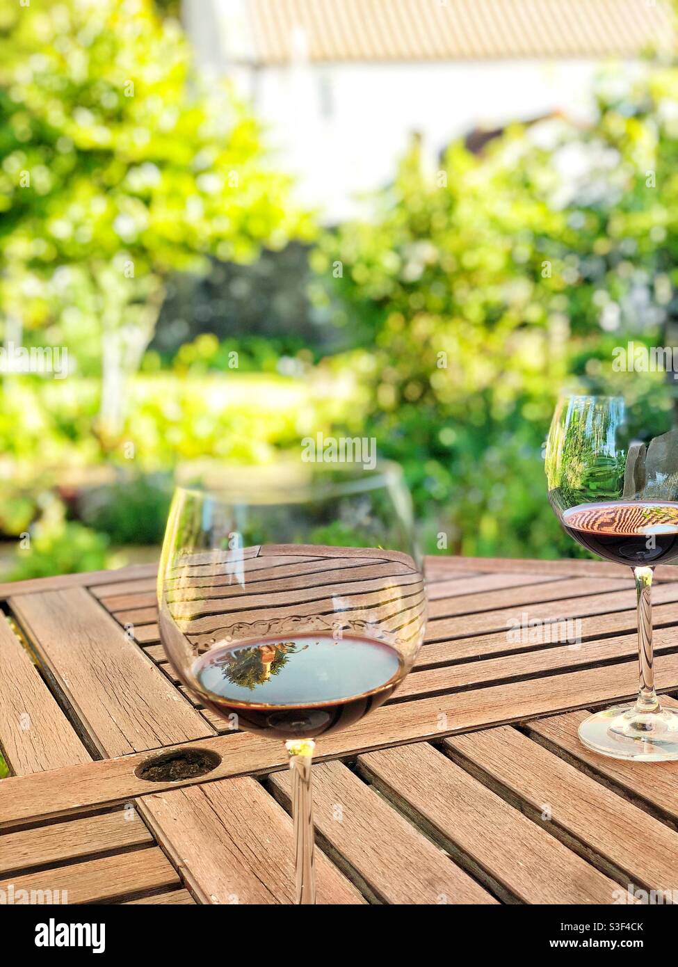 Zwei Gläser Rotwein in großen übergroßen Gläsern Der Gartentisch bei Sonnenschein im Sommer Stockfoto