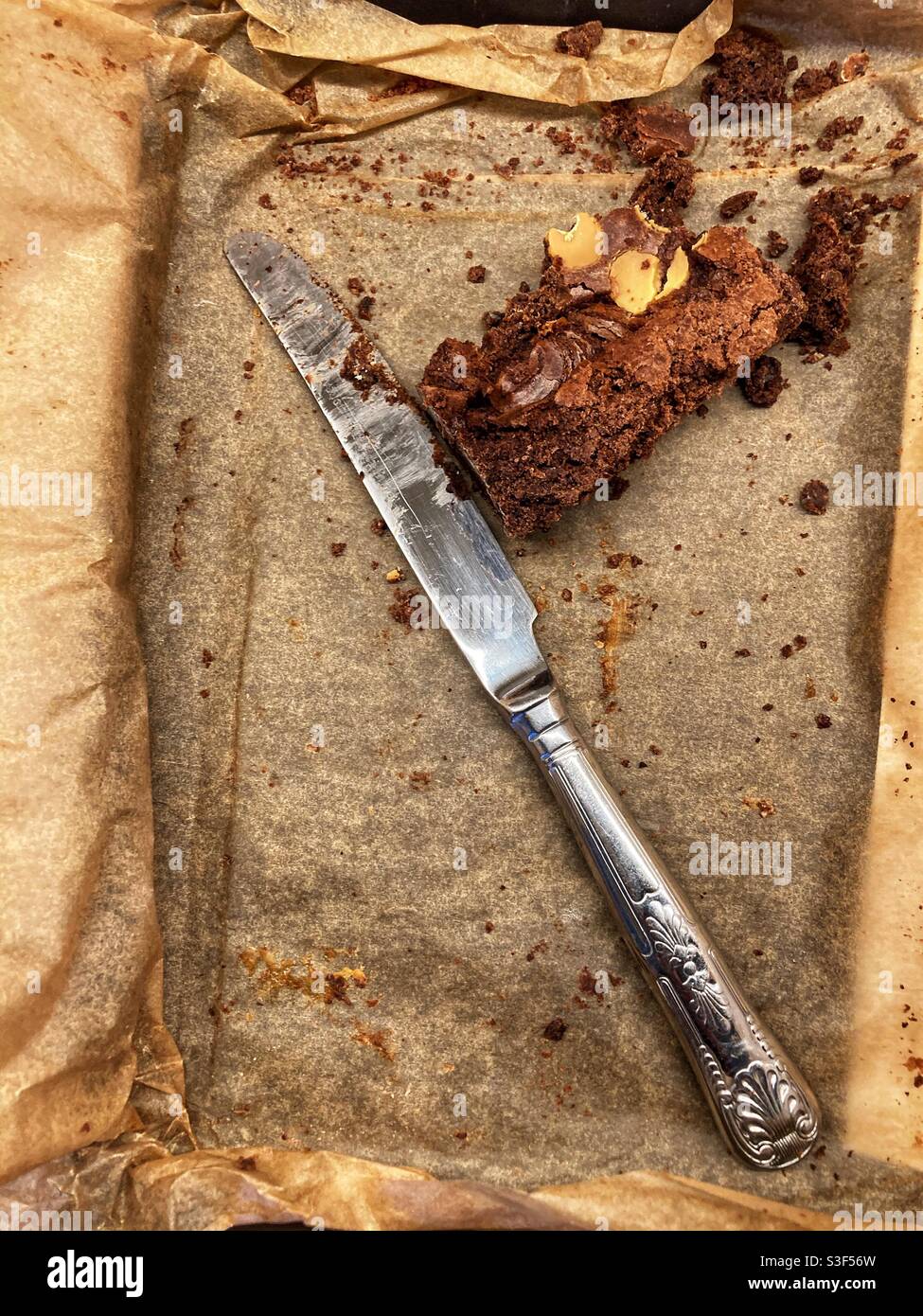 Die Reste eines Schokoladenbrownie mit einem gebrauchten Messer Daneben Stockfoto