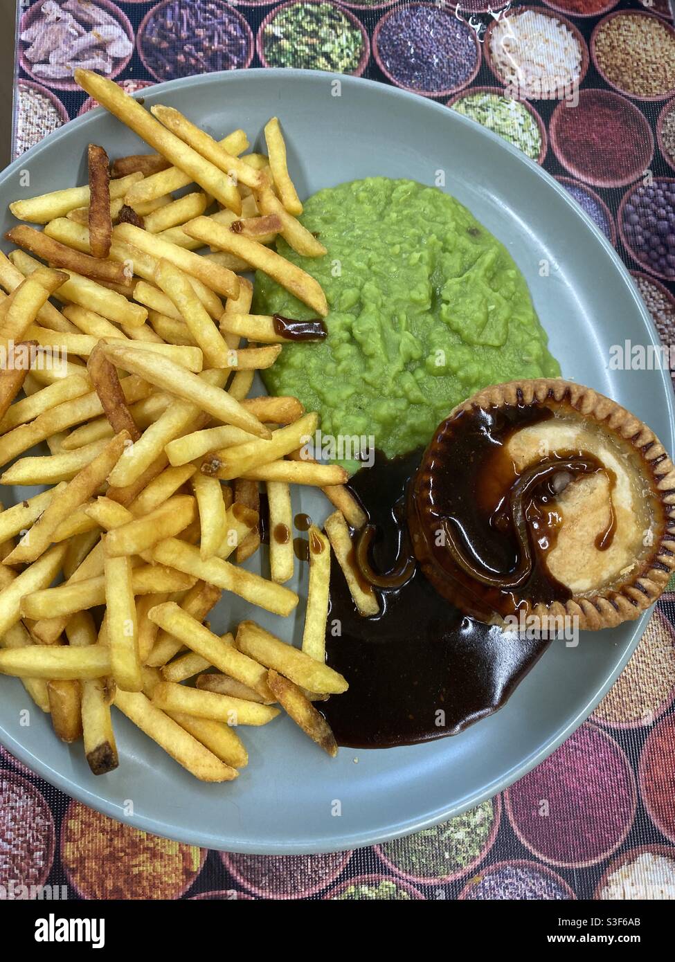 Pie, Zwiebelsoße, Pommes und matschige Erbsen - Smartphone-aufgenommenes Stockfoto