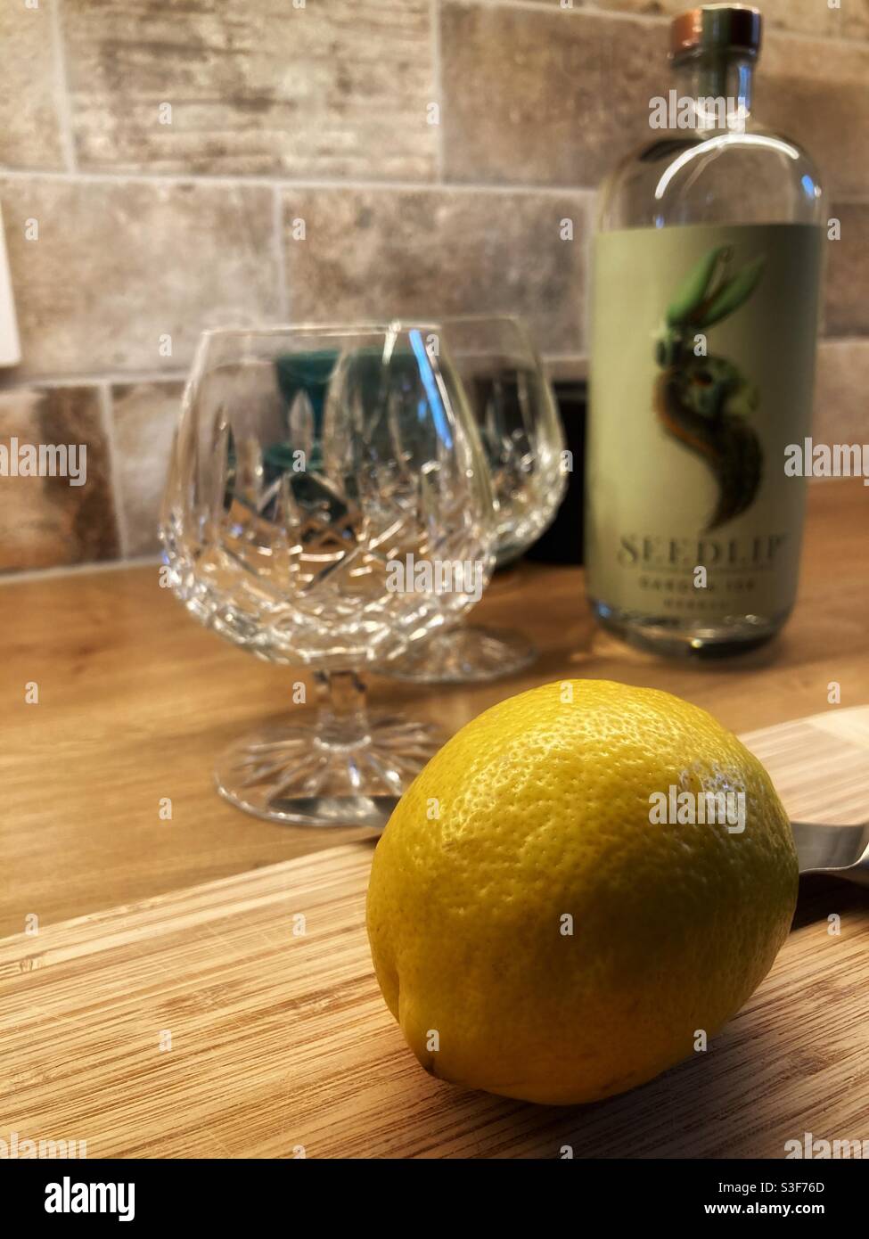 Seedlip alkoholfreie destillierte Spirituosen und tonische Getränke werden vorbereitet - Zitrone, die im Vordergrund geschnitten werden soll Stockfoto
