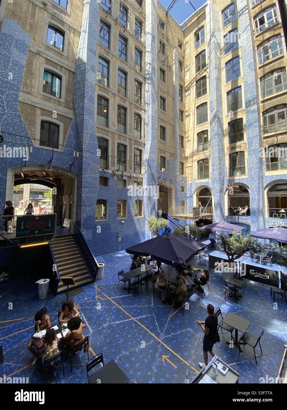 Food Court Hall in Open Sky Mall Les Docs mit Glasdach und blauem Boden und Wänden in Marseille, Provence Alpes Côte d’Azur - Smartphone-aufgenommenes Stockfoto