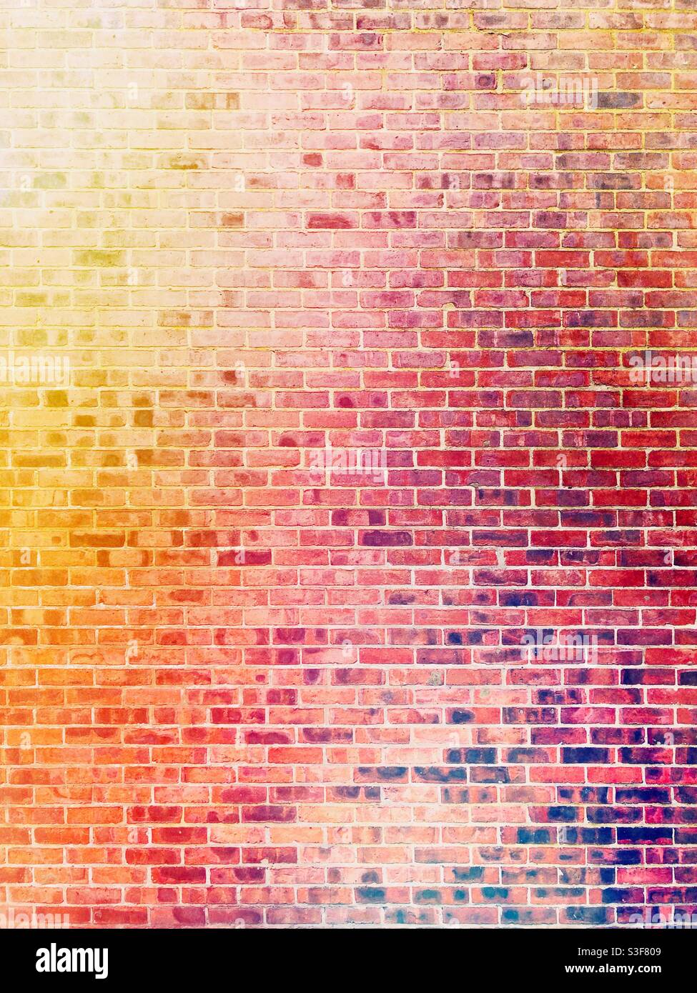 Ein Vollformathintergrund von einem bunten und hell erleuchteten Rote Ziegelwand mit gelben und roten Farbtönen mit Kopie Platz Stockfoto