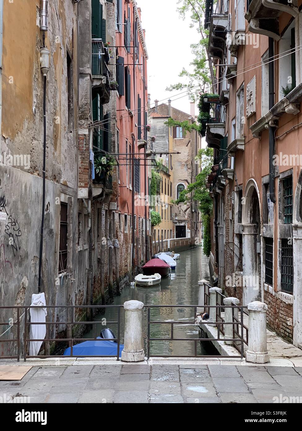 Sehr enger Kanal zwischen älteren farbigen Gebäuden in San Polo, Venedig, Italien. - Smartphone-aufgenommenes Stockfoto