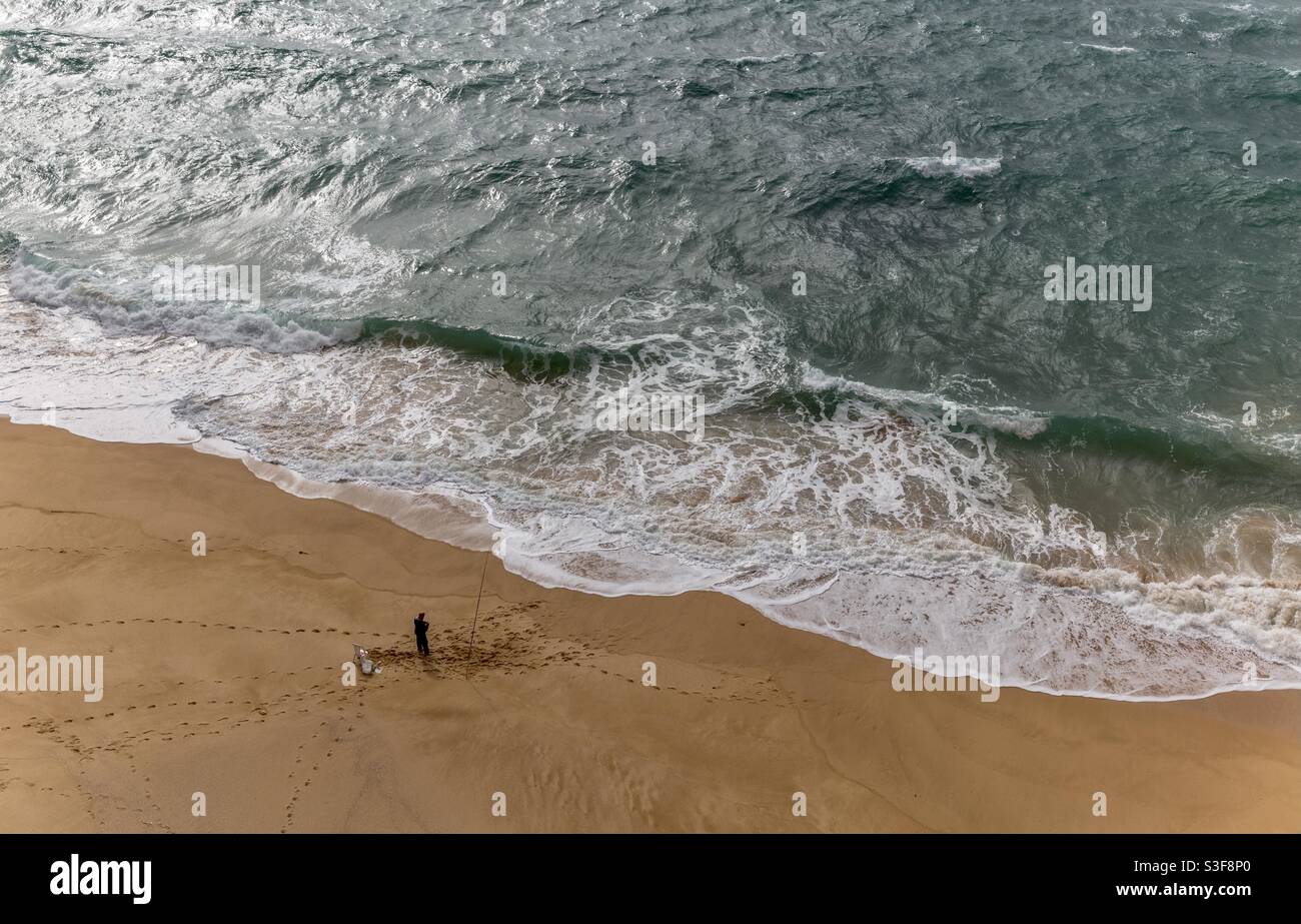 Ein Fischer fängt an einem der südlichen Strände Fisch Des Atlantiks in Portugal Stockfoto