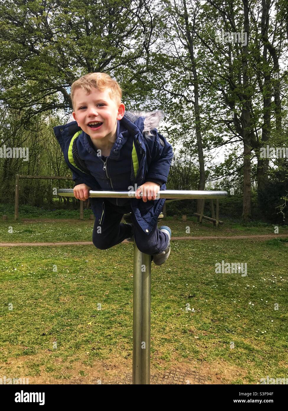 Glücklicher, vierjähriger Junge, der im Park spielt. Medstead Village Green, Hampshire, England. Stockfoto