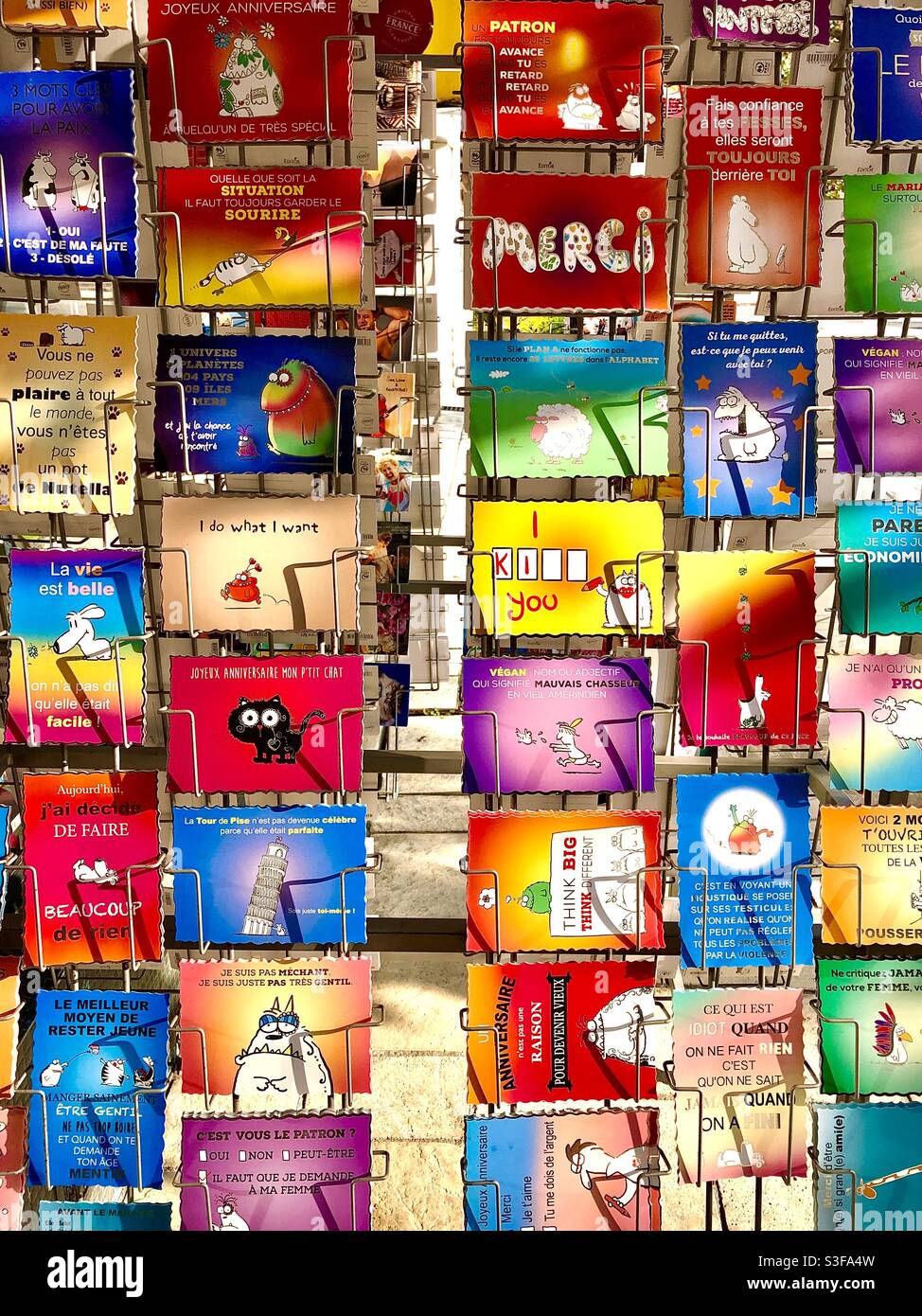 Ein Regal mit lustigen Postkarten vor dem französischen Laden. Stockfoto