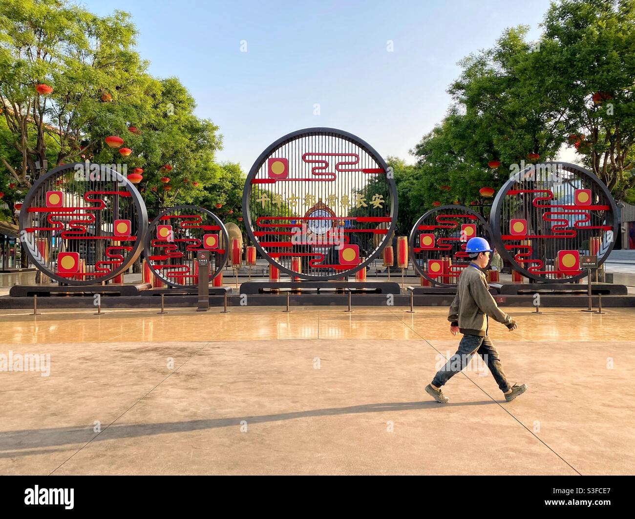 Xian, China – 7. Mai 2021: Ein Bauarbeiter, der die berühmte Yanta South Road in Xian, China, entlang läuft - Smartphone-aufgenommenes Stockfoto