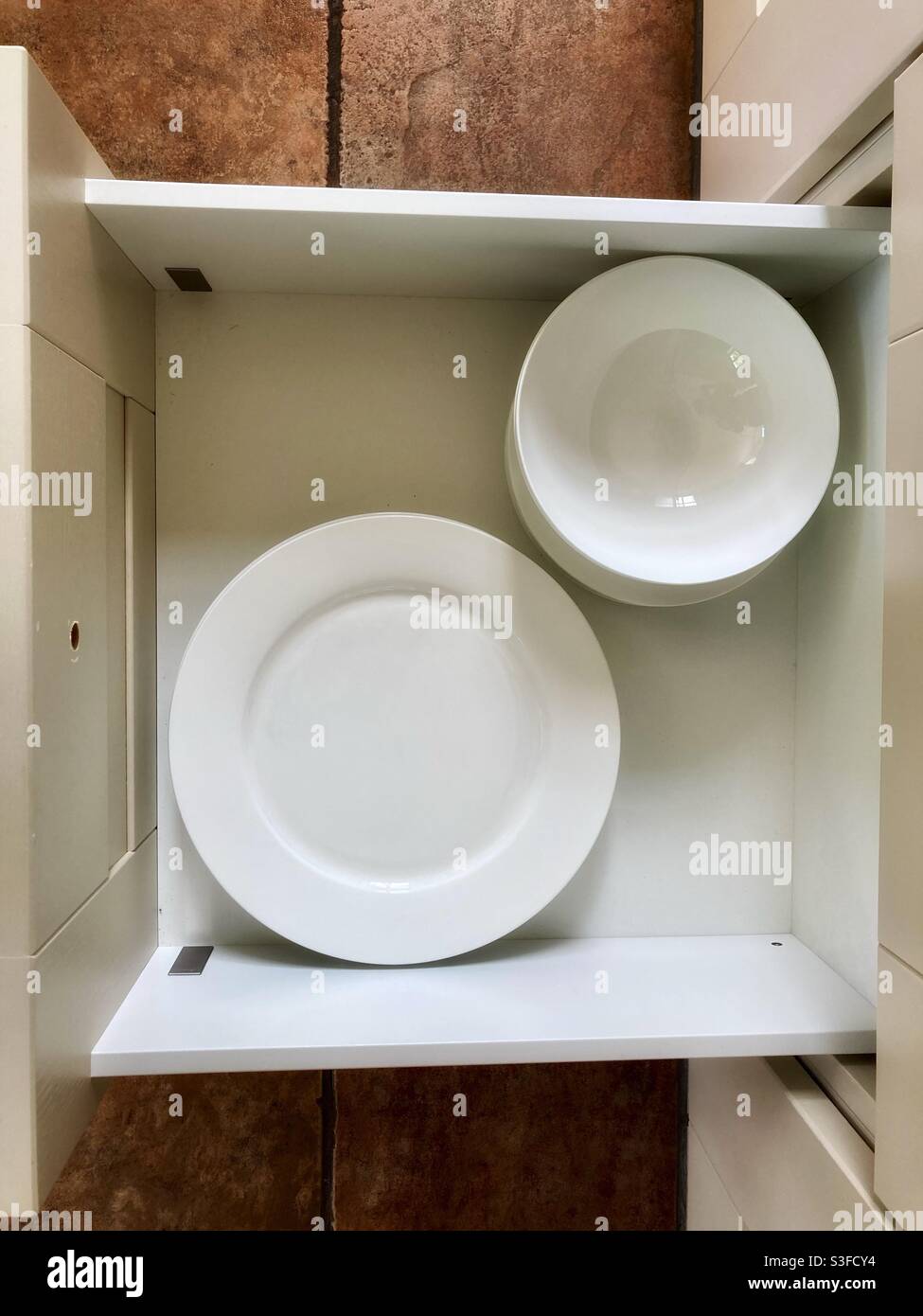Teller-Schublade mit weißen Tellern und Schüsseln von oben - Geschirr Stockfoto