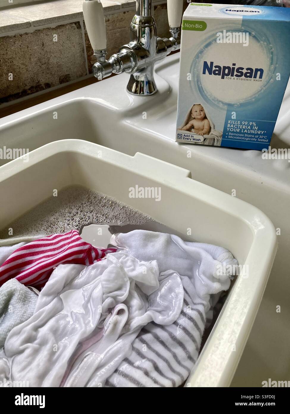 Einweichen von Babykleidung im Waschbecken/Spülbecken Verwendung von Napisan- Wäsche Stockfoto