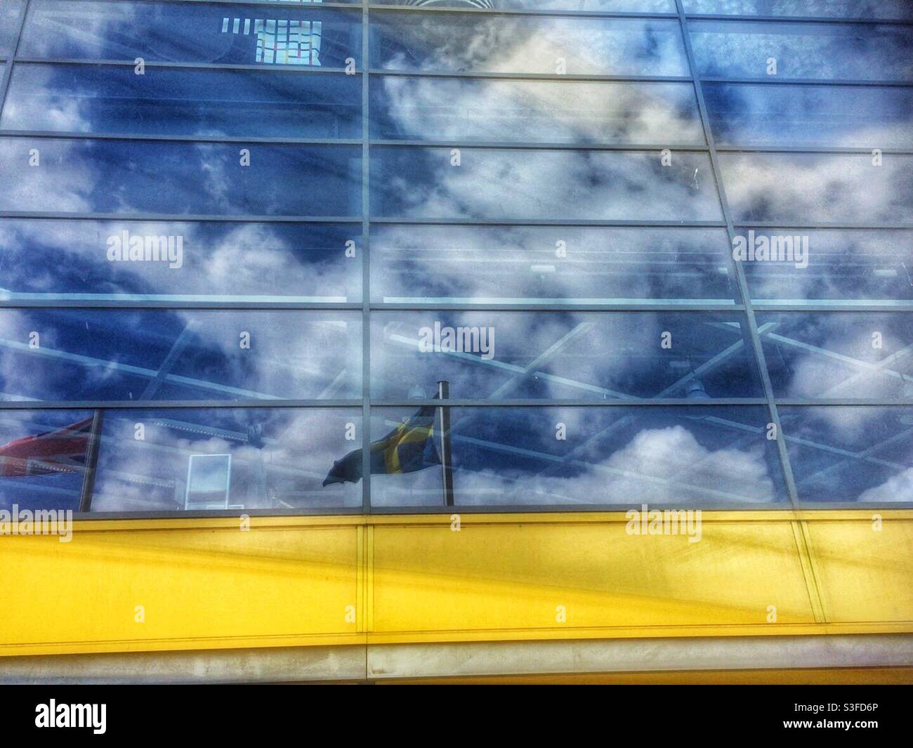 Spiegelung in einem IKEA-Schaufenster mit Wolken, blauem Himmel und Fahnen Stockfoto