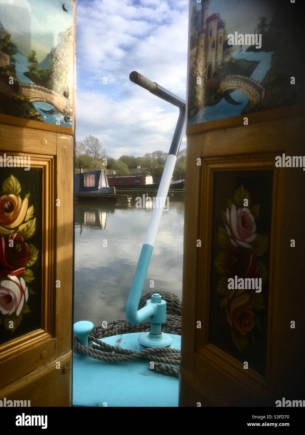 Blick vom Heck eines Schmalbootes über das Wasser auf andere Boote und zeigt typische Dekoration zu den Holztüren. - Smartphone-aufgenommenes Stockfoto