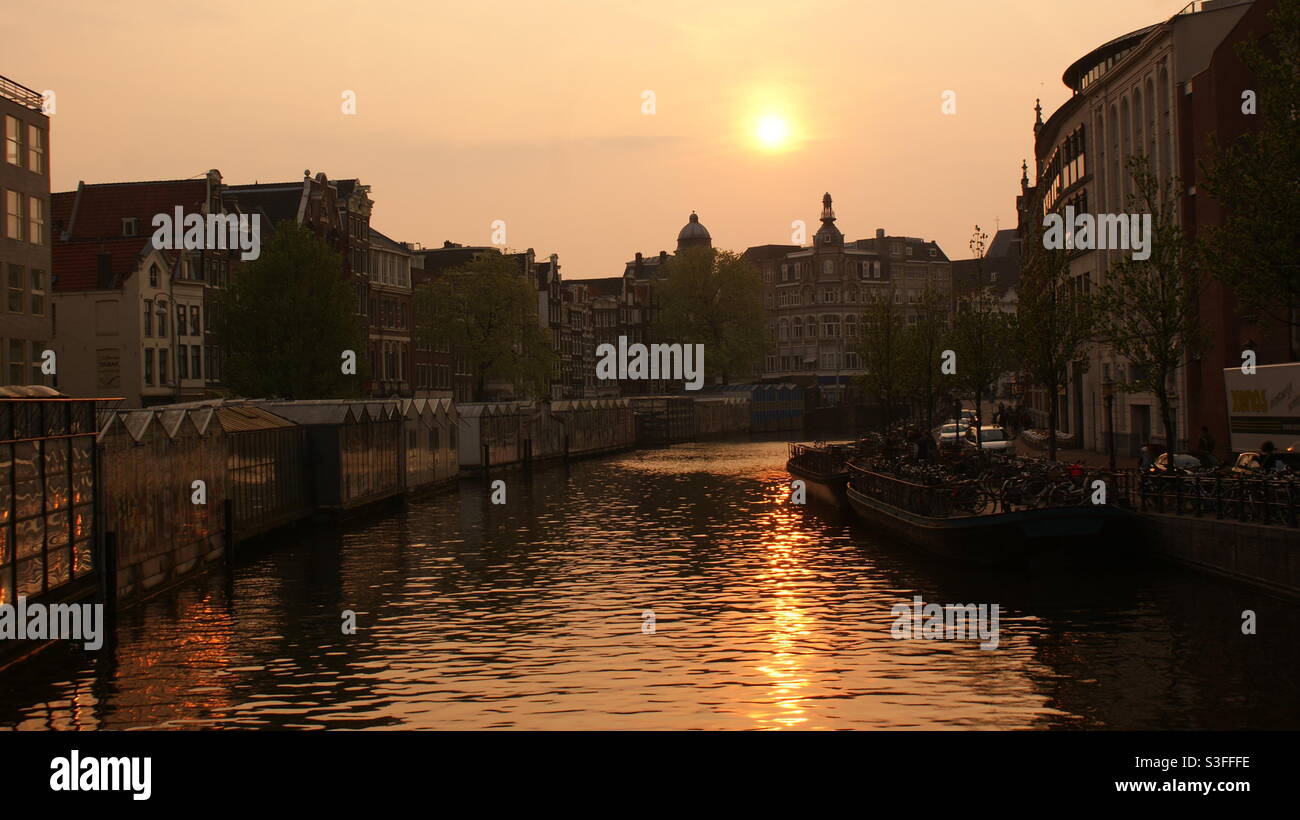 Sonnenuntergang mit Reflexionen im Kanal von Amsterdam Stockfoto