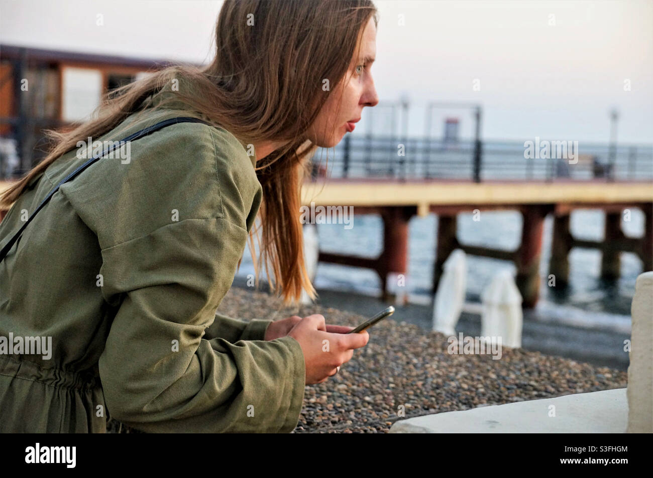 Mädchen mit langen Haaren Blick auf das Meer - Smartphone-aufgenommenes Stockfoto