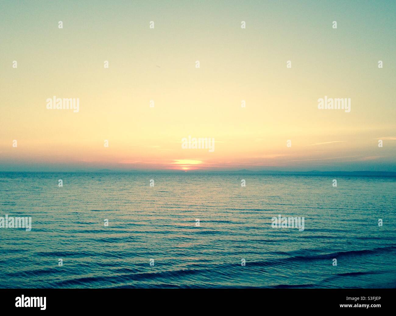 Sonnenuntergang über einem nebligen blauen Meer in Wales, Großbritannien - Kopierraum, keine Menschen Stockfoto