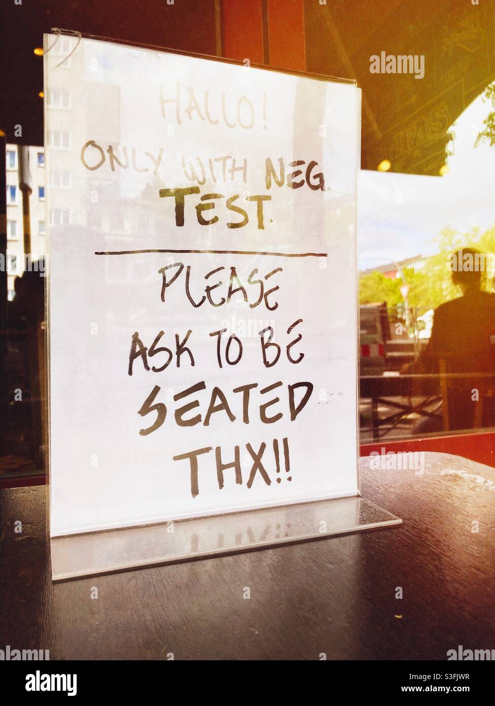 Melden Sie sich in einem Burger Restaurant in Berlin an, um zu sagen, dass nur Kunden mit negativen Corona-Tests bedient werden und nach einem Sitzplatz fragen müssen, Berlin, Deutschland - Smartphone-aufgenommenes Stockfoto