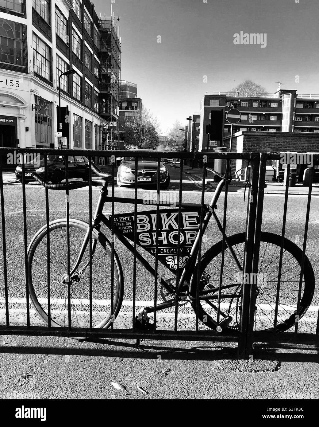 Schwarz-Weiß-Foto des Fahrrads, das am Geländer befestigt ist Stockfoto