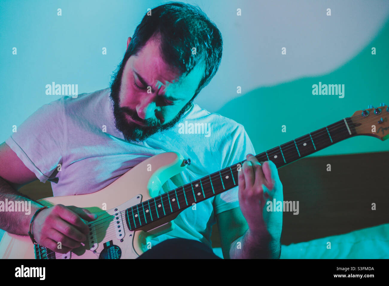 Ein Gitarrist, der solo, pink und blau leuchtet Stockfoto