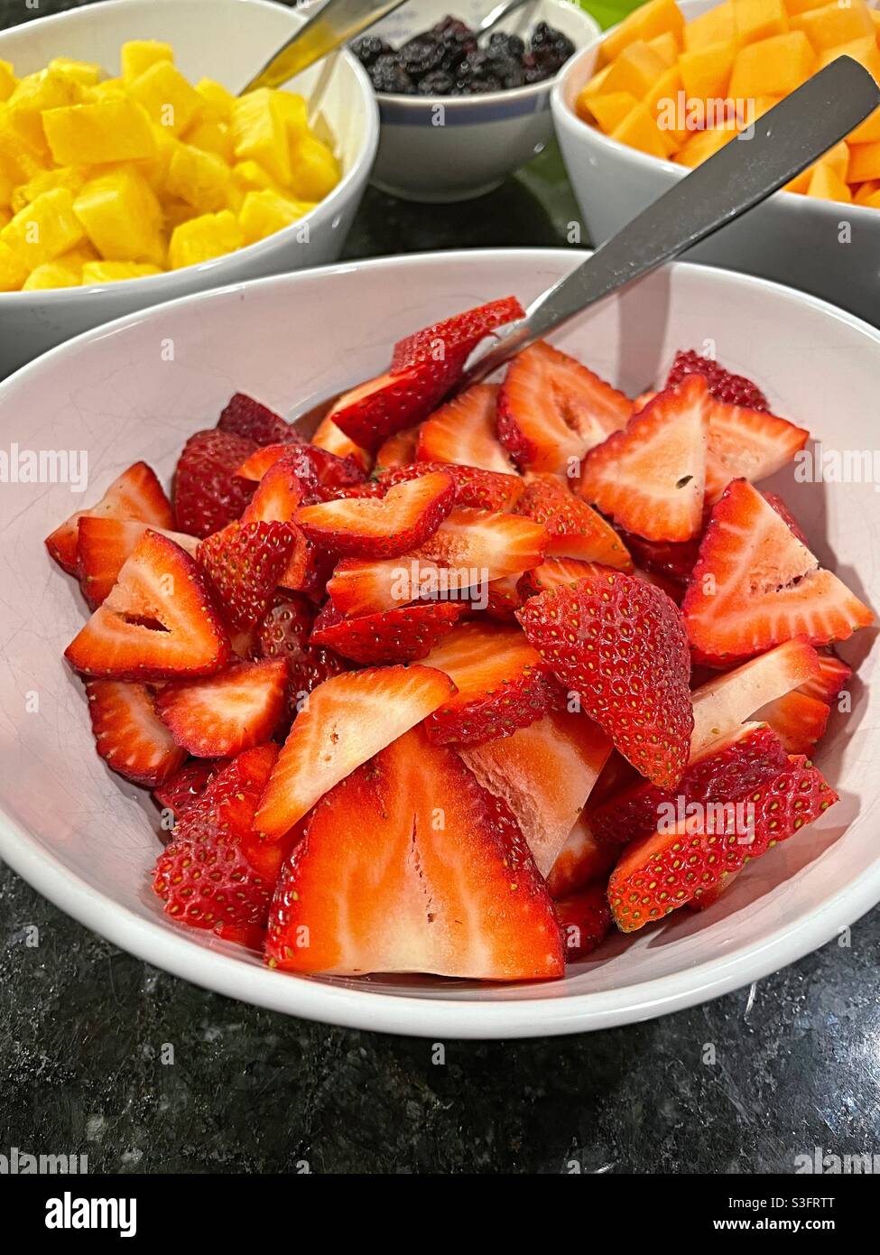 Schüsseln mit Erdbeeren und anderen Früchten an einem Büfettetisch, USA - Smartphone-aufgenommenes Stockfoto