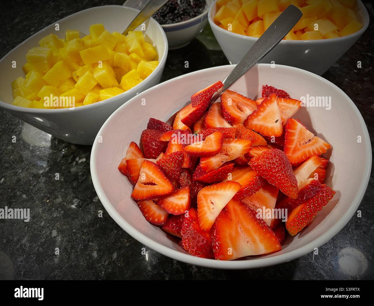 Schüsseln mit frisch geschnittenem Obst auf einem privaten Buffettisch, USA - Smartphone-aufgenommenes Stockfoto