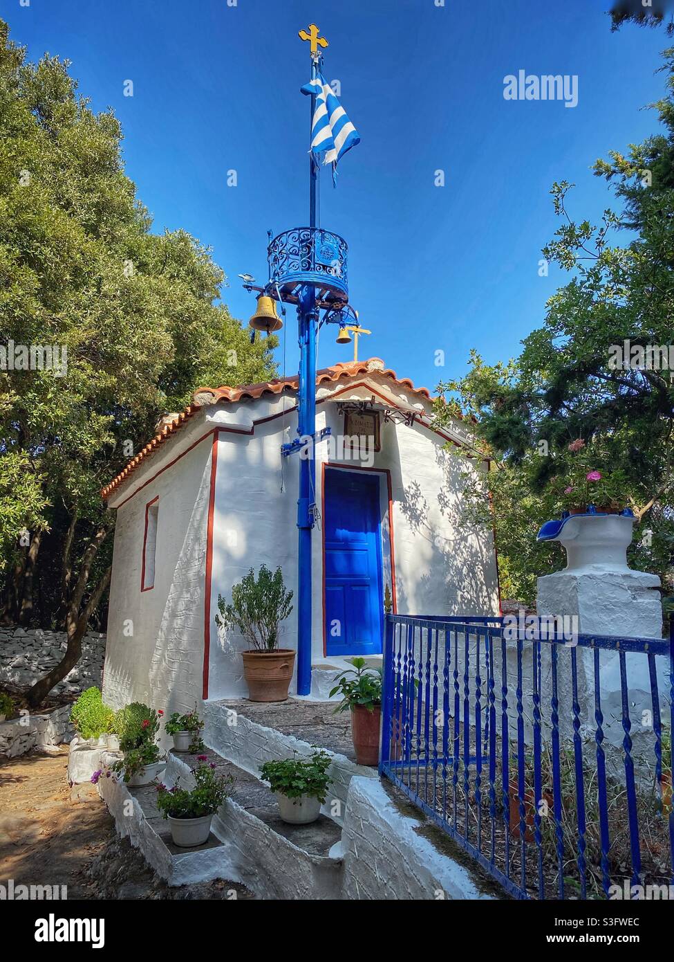 Kleine griechische Kirche mit griechischer Flagge im Norden der Insel Skiathos. - Smartphone-aufgenommenes Stockfoto