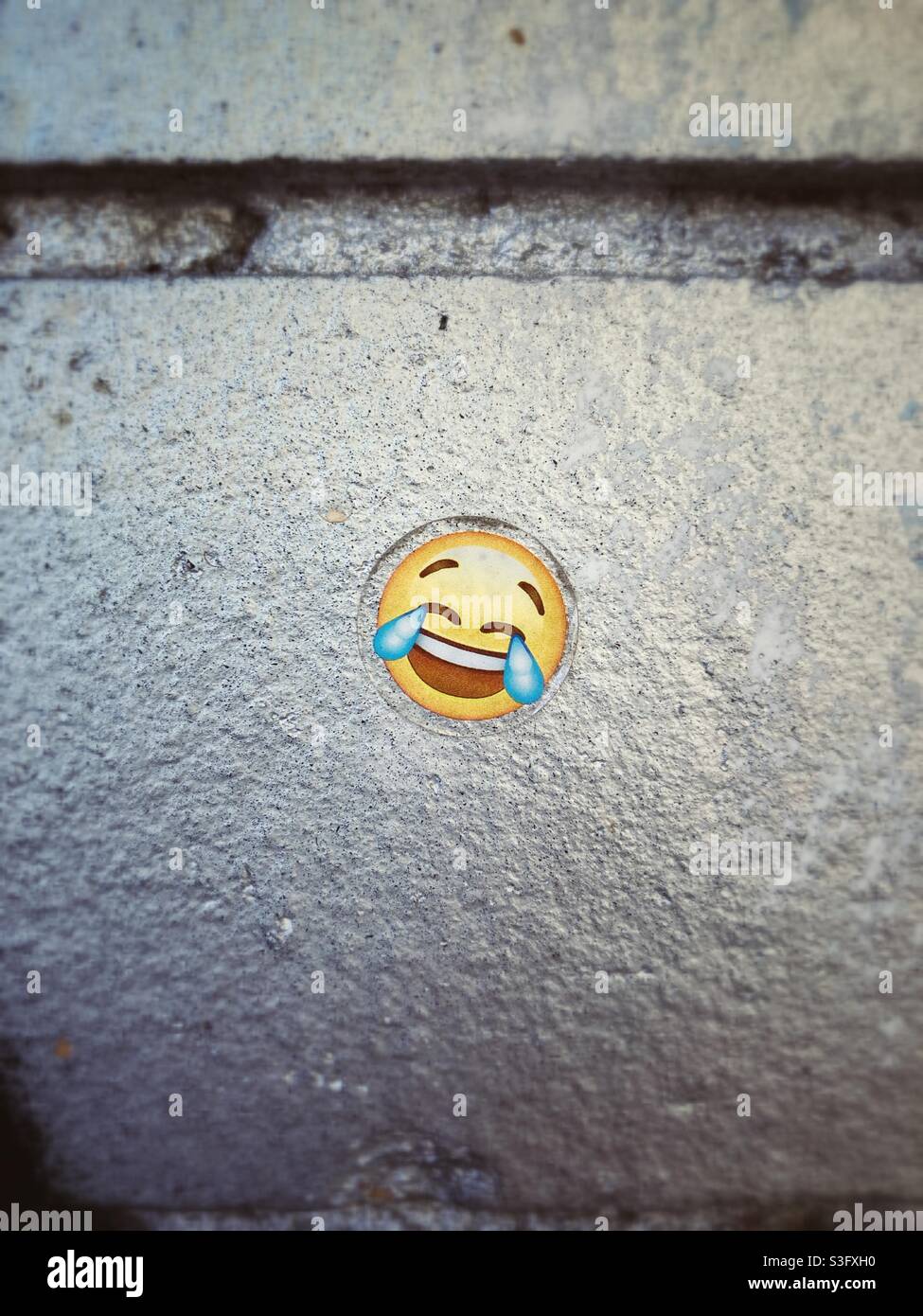 Lachende Tränen Emoji-Aufkleber auf einer silbernen Wand Stockfoto