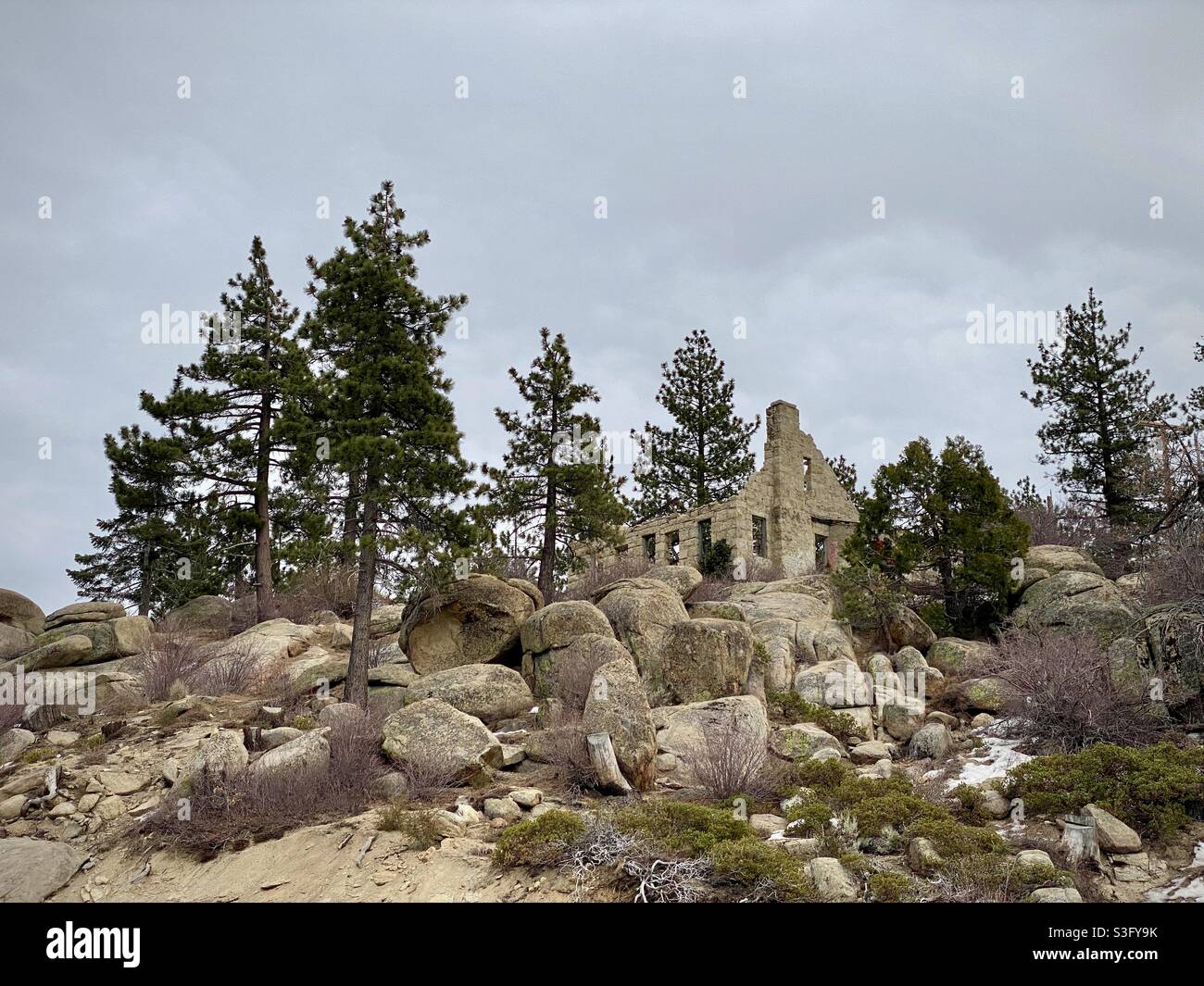 Überreste eines verlassenen Hauses auf einem felsigen Hügel mit Pinien im San Bernardino National Forest am Big Bear Lake, Kalifornien, 2020 - Smartphone-aufgenommenes Stockfoto