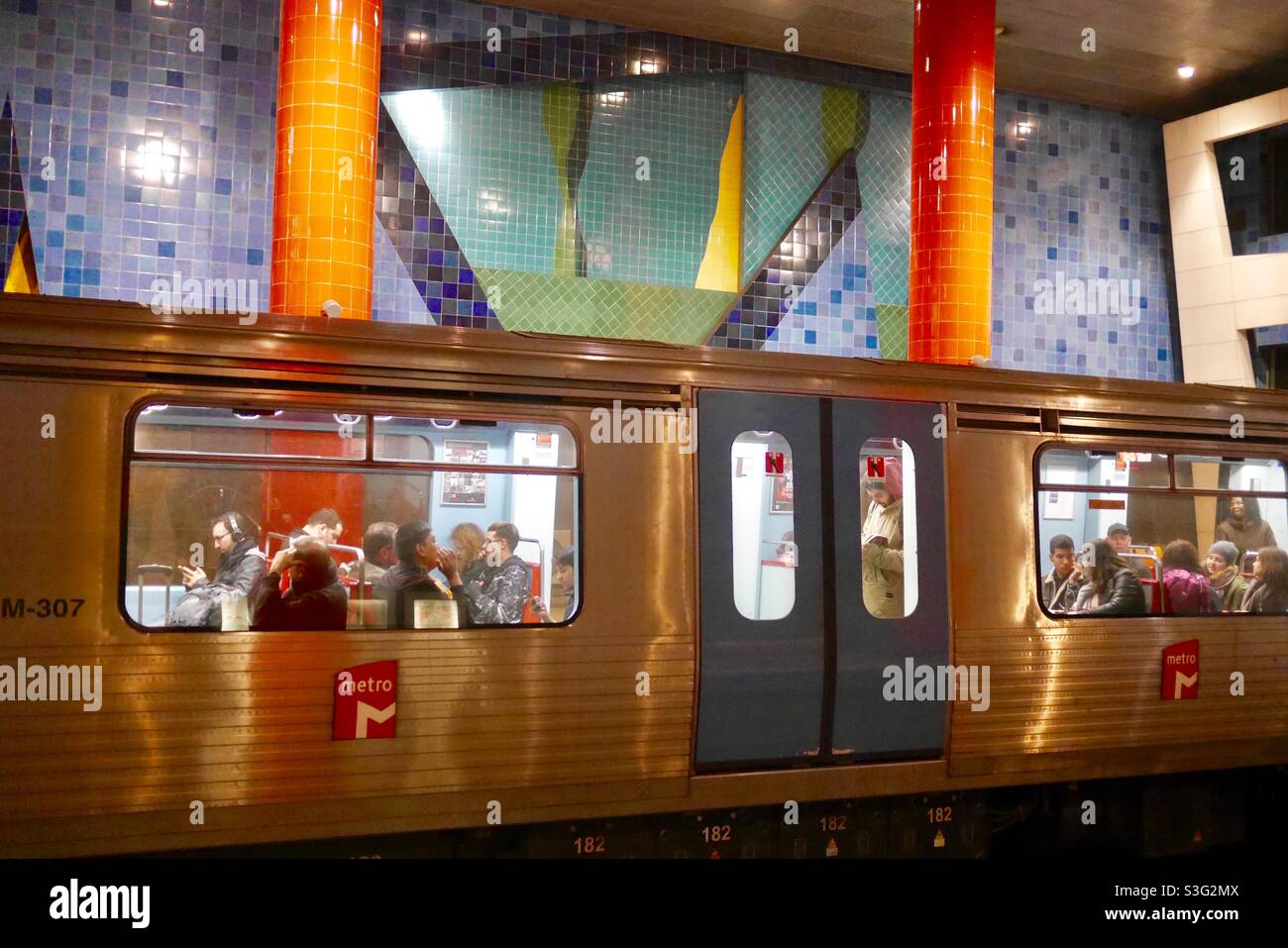 Madrider Metrowagen voller Passagiere im Bahnhof mit lebhaften Kachelkunstwerken Stockfoto