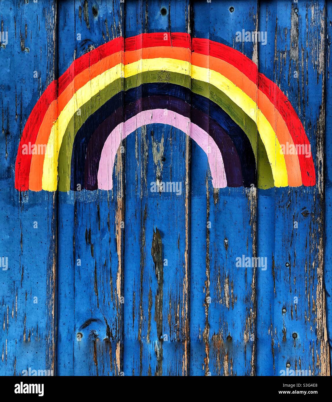 Ein farbenfroher Regenbogen, der auf eine strukturierte Holztür gemalt wurde, von Kindern, die dem britischen Gesundheitsministerium danken Stockfoto