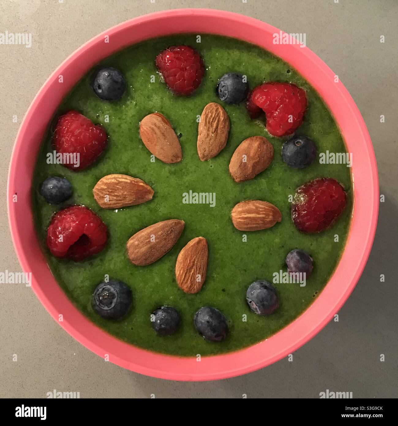 Grünes und gesundes Frühstück mit roten Früchten und Mandeln Stockfoto