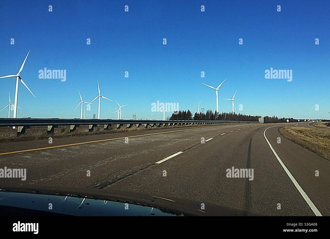 Fahrt auf einer Autobahn an einem Ufer von Windmühlen, Nova Scotia, Kanada. Blick vom Beifahrersitz in einem fossilen SUV. Konzepte: Energie-Ironie, alt und neu, Vergangenheit und Zukunft. - Smartphone-aufgenommenes Stockfoto