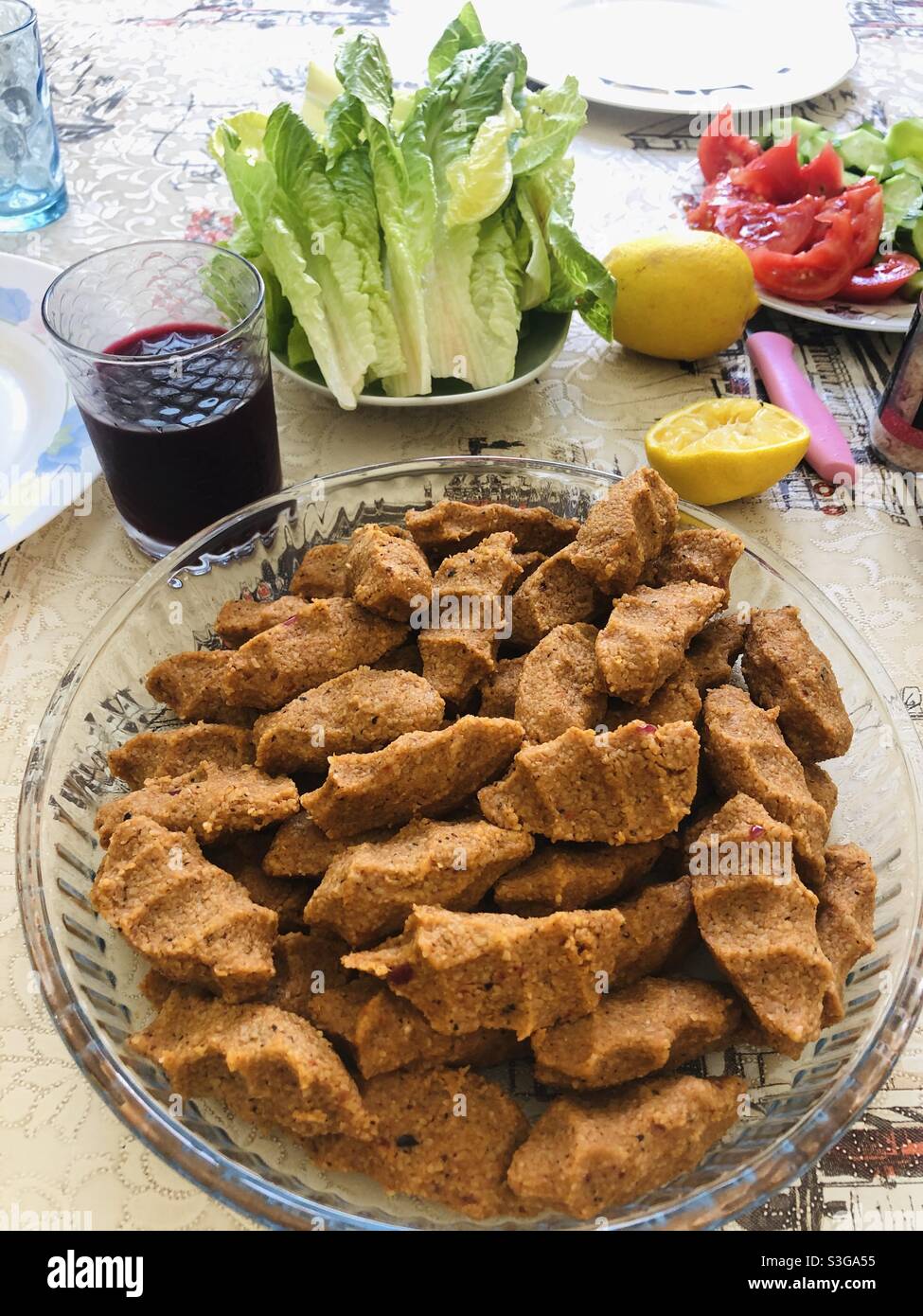 Türkisches veganes Gericht namens Cig Kofte, das mit Gemüse und Rübensaft serviert wird Stockfoto
