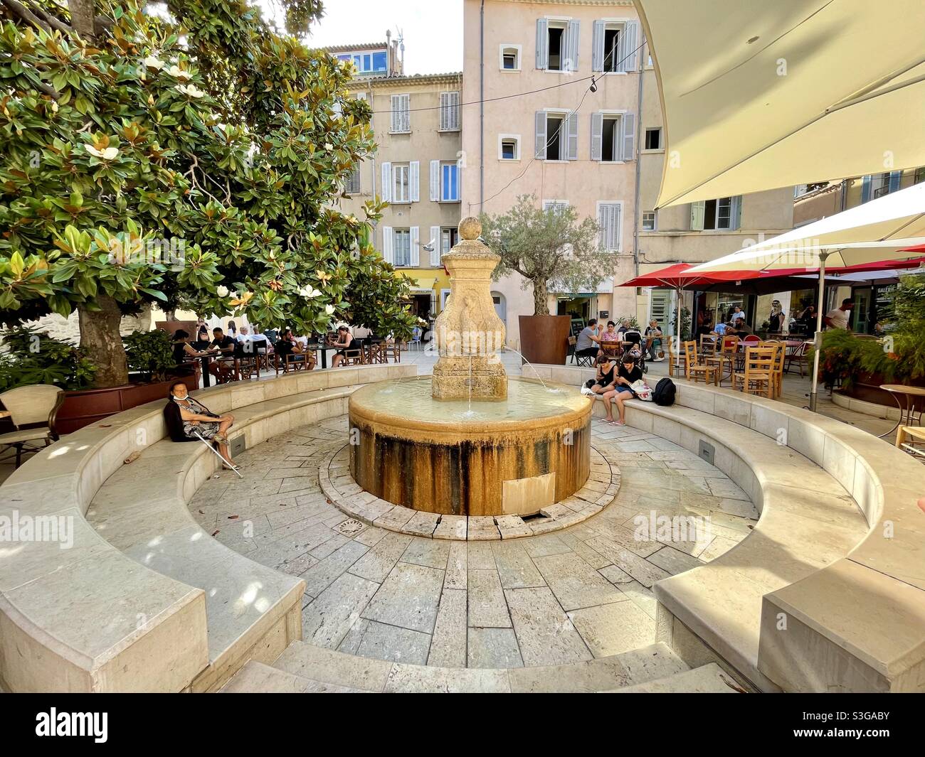 Alte öffentliche Waschplatz Brunnen umgeben von Bäumen, Blumen und Restaurants in der Innenstadt von La Ciotat, in der Nähe von Marseille, Bouches-du-Rhône, Provence-Alpes-Côte d'Azur, Südfrankreich Stockfoto