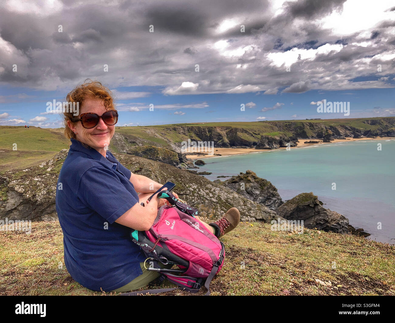 Frau saß auf der Klippe über Mackerel Cove Cornwall Stockfoto
