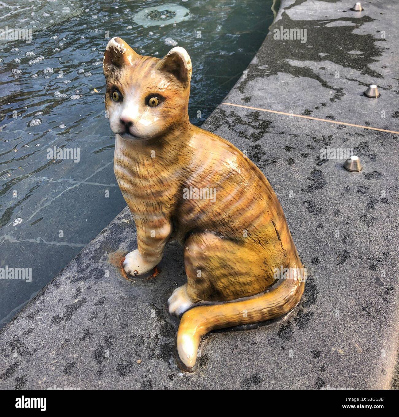 Eine Katzenstatue an der Seite eines Wasserbrunnens. Stockfoto